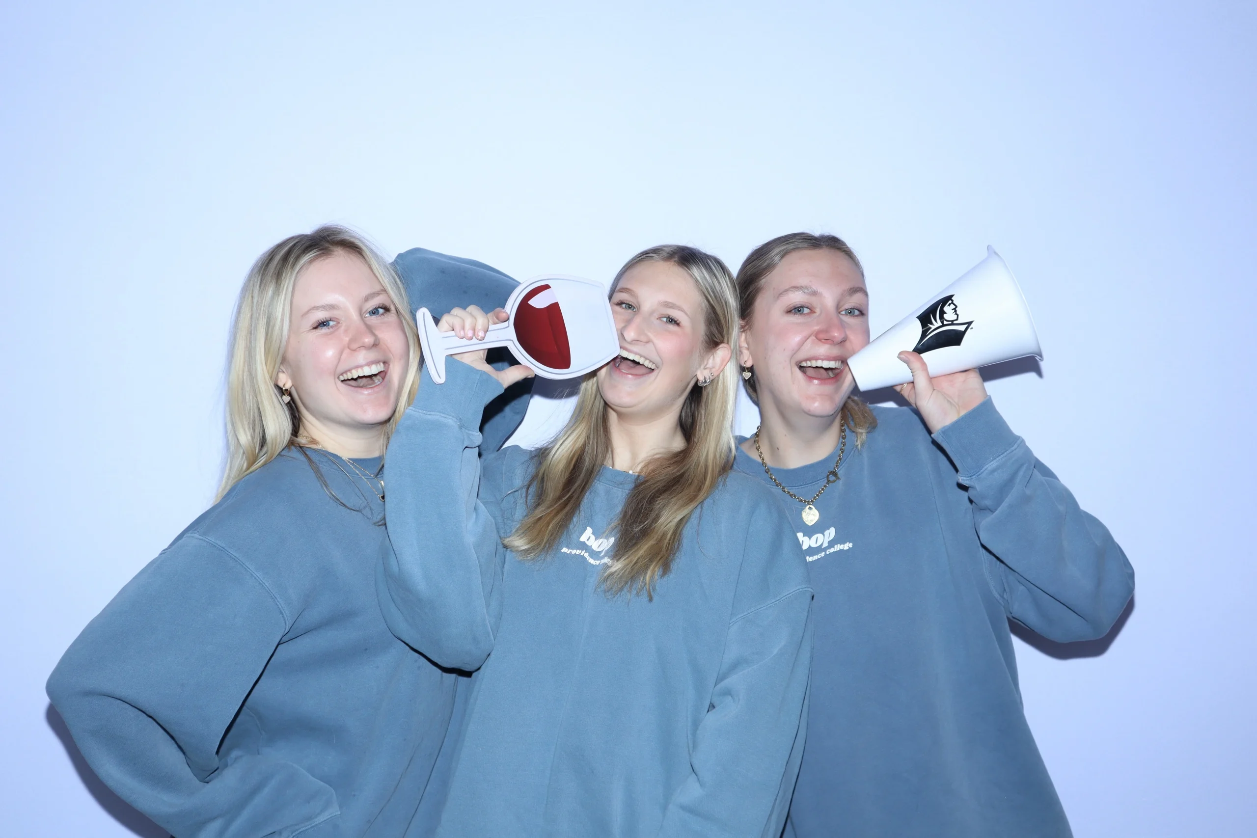 girls pose in photo booth with flat white backdrop