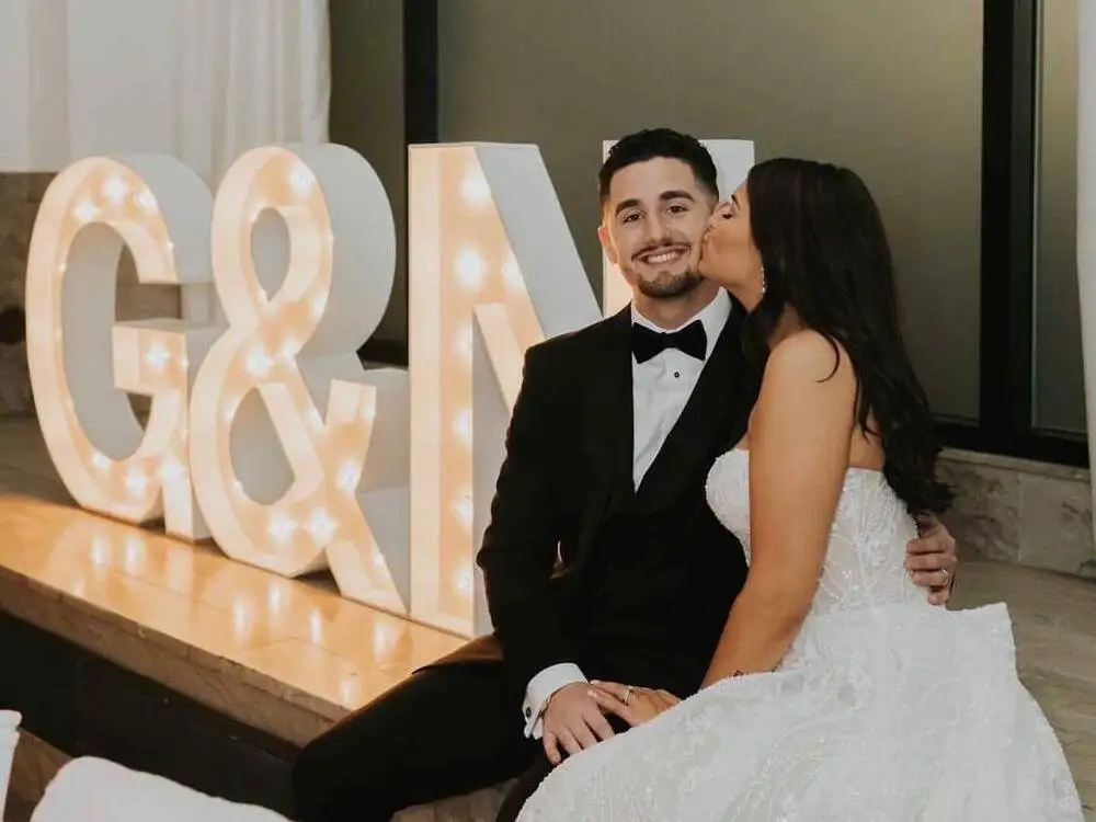 bride and groom sit with light-up marquee letters